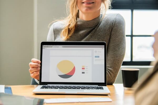 Image of a woman holding open a laptop computer with charts and graphs.